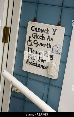 Veuillez appeler pour obtenir de l'aide si vous êtes invalide, bilingue anglais Welsh language sign in butcher s shop UK Wales Cardigan Banque D'Images