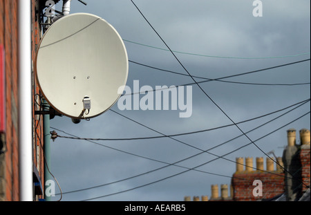 Une grande antenne satellite s'est assis sur le côté de la maison, grâce à des fils téléphoniques criss crossing derrière dans la rue Banque D'Images