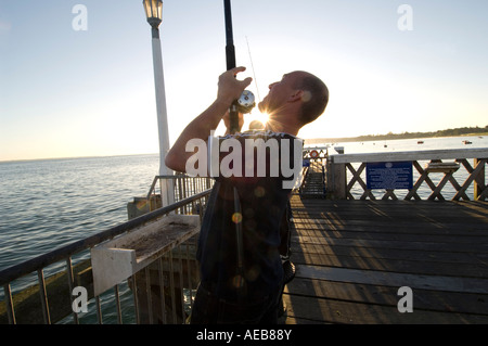 Un pêcheur du maquereau sur la jetée de Yamouth sur l'île de Wight tôt un matin que le soleil se lève. Banque D'Images