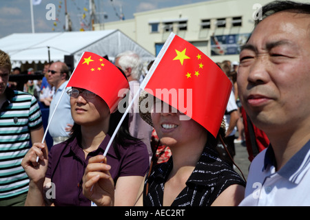 Les femmes chinoises et un homme utiliser des petits drapeaux chinois comme la protection contre le soleil dans la rue de l'Europe Suède Göteborg Banque D'Images