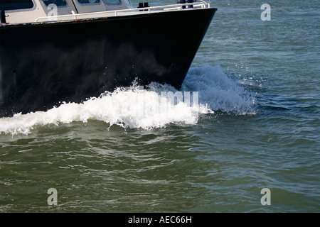 Sur la crête d'une vague. La proue d'un bateau traversant l'eau créant une vague. Banque D'Images