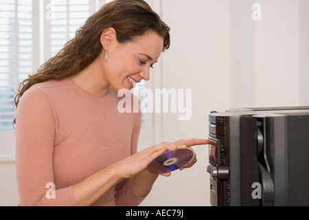Hispanic woman putting cd en stéréo Banque D'Images