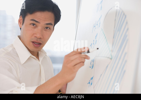 Asian businessman writing on whiteboard Banque D'Images