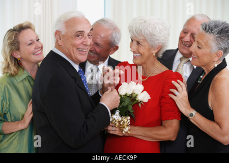 Hauts homme donnant à l'épouse bouquet de fleurs tandis que les amis regardez Banque D'Images