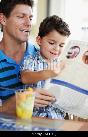 Hispanic father and son reading menu au restaurant Banque D'Images