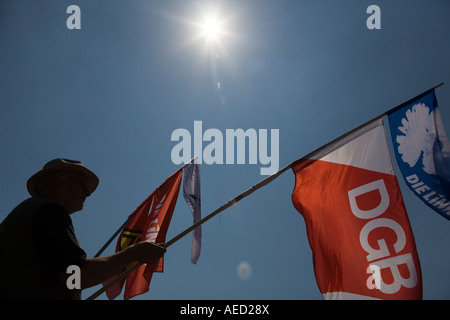 Un homme silhouetté contre le sun détient les drapeaux tout en assistant à la dernière manifestation contre la réunion du G8 de 2008. Banque D'Images