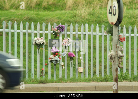 Tributs floraux et une plaque fixée au fer forgé et à 40 milles à l'heure de la route où il y a eu un accident mortel Banque D'Images