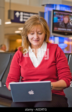 Belle femme assise dans aérogares avec ordinateur portable Banque D'Images