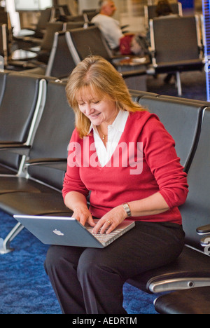 Belle femme assise dans aérogares avec ordinateur portable Banque D'Images