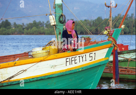 Cham femme portant foulard krama traditionnel assis dans un bateau de pêche, la rivière Sanke, Kampot, Cambodge Banque D'Images