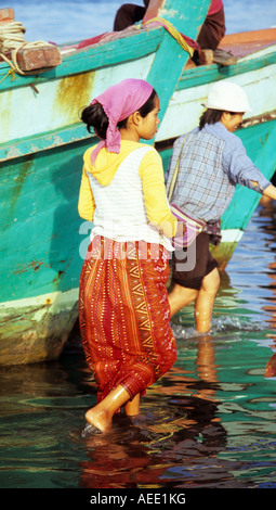 Femme Cham en paréo coloré article par bateaux de pêche sur la rivière Sanke, Kampot, Cambodge Banque D'Images