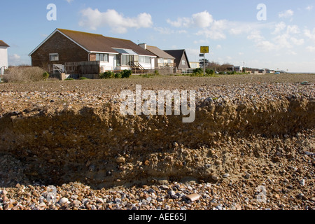 Maisons à proximité du front d'érosion sur une plage de Sussex Banque D'Images