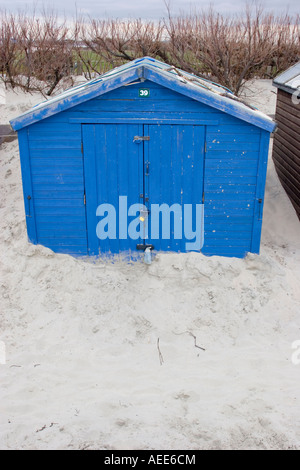 Cabane de plage à moitié enfoui dans une dune de sable dans la région de West Wittering Banque D'Images