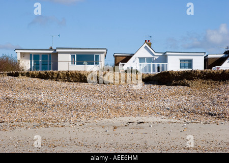 Maisons à proximité du front d'érosion sur une plage de Sussex Banque D'Images