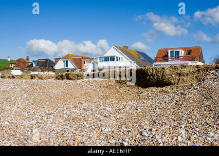 Maisons à proximité du front d'érosion sur une plage de Sussex Banque D'Images