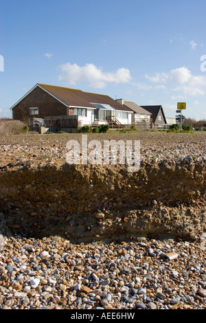 Maisons à proximité du front d'érosion sur une plage de Sussex Banque D'Images