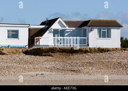 Maisons à proximité du front d'érosion sur une plage de Sussex Banque D'Images