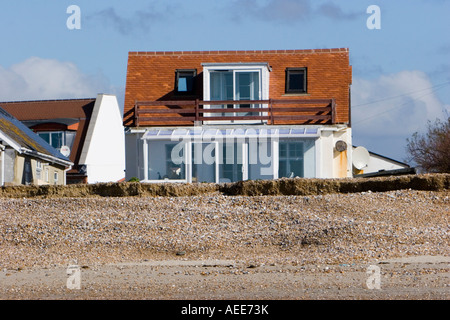 Maisons à proximité du front d'érosion sur une plage de Sussex Banque D'Images