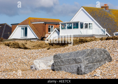 Maisons à proximité du front d'érosion sur une plage de Sussex Banque D'Images