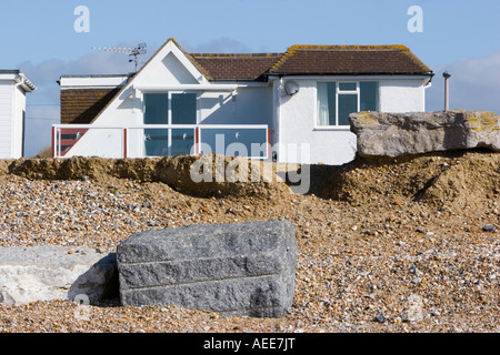 Maisons à proximité du front d'érosion sur une plage de Sussex Banque D'Images