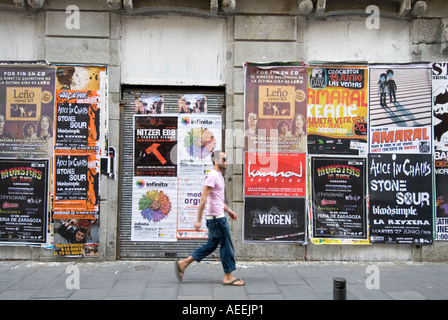 Homme marchant passé fly publicité affiches rock de zone Chueca, Madrid Espagne Banque D'Images