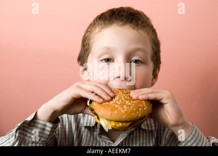 Boy eating hamburger chez McDonald's, England, UK Banque D'Images