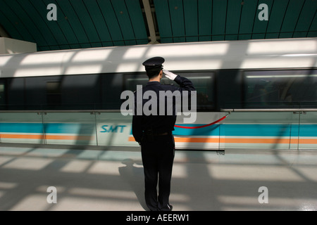 Un garde salue le train à sustentation magnétique Maglev qui transporte les passagers de Longyang Lu gare à l'aéroport de Pudong Banque D'Images