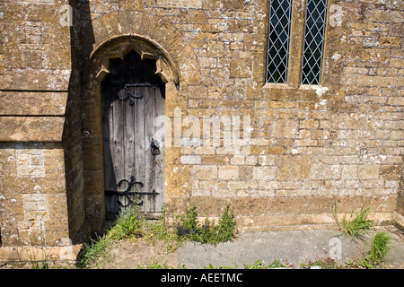 Vieille porte latérale en bois à St John the Baptist Church Broadwindsor Dorset ancien porte latérale en bois mur en pierre bois noueux Banque D'Images