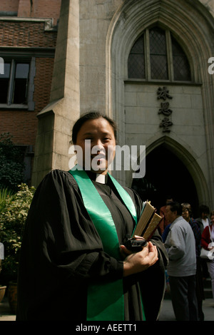 La femme prêtre salue les membres de la congrégation après le service à l'église catholique en um à Shanghai Banque D'Images