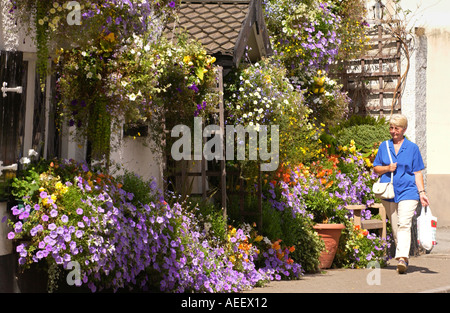 Dame marcher passé affichage floral au Cross Keys pub partie de fête des fleurs dans la ville rurale de l'Usk Monmouthshire au Pays de Galles UK Banque D'Images