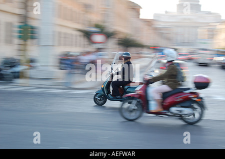 Scooters chevauchant dans la rue animée de la ville en Italie avec effet de flou de mouvement. Scène de transport urbain dans la ville européenne historique. Rome, Italie. Banque D'Images