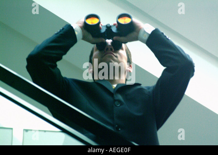 Businessman holding binoculars à regarder peeping curieux prying window personnes personne mâle homme hors du bureau d'affaires conc Banque D'Images