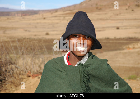 Garçon Herder en cape verte et un chapeau dans les montagnes du Lesotho à sec Banque D'Images