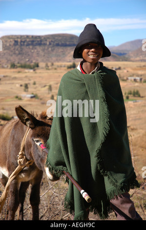 Garçon Herder en cape verte et un chapeau dans les montagnes du Lesotho à sec Banque D'Images