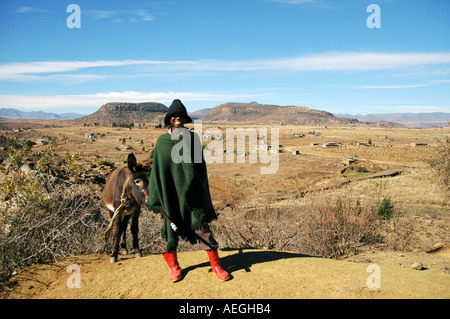 Garçon Herder en cape verte et un chapeau dans les montagnes du Lesotho à sec Banque D'Images