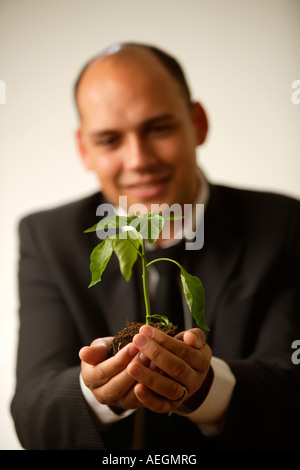 Young Woman holding doucement une petite usine, focus on foreground Banque D'Images