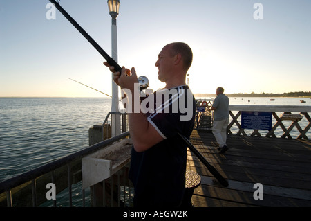 Un pêcheur du maquereau sur la jetée de Yamouth sur l'île de Wight tôt un matin que le soleil se lève. Banque D'Images