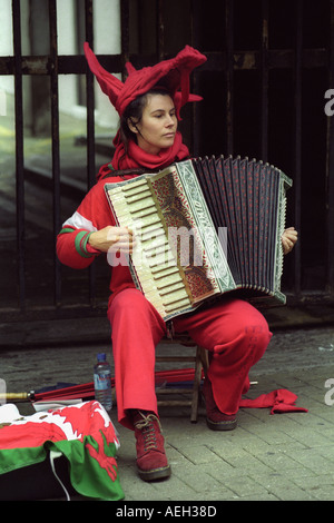 Joueur d'Accordéon musicien ambulant dans un costume de dragon rouge dans les rues de Cardiff au Pays de Galles avant un match de rugby international UK Banque D'Images