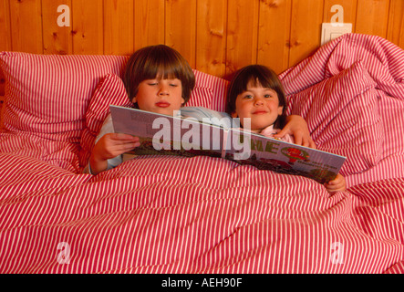 Deux enfants de la lecture d'un livre pour enfants au lit. Photo par Willy Matheisl Banque D'Images