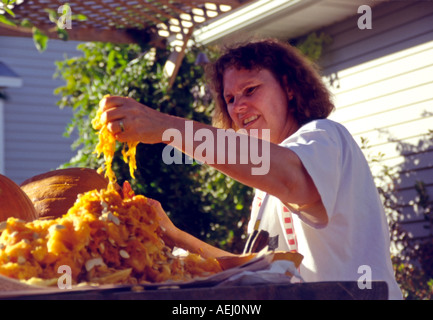 Une femme nettoie plusieurs citrouilles, sur une terrasse extérieure avec table, avant qu'une partie de la sculpture de la famille dans l'Utah, USA. Banque D'Images