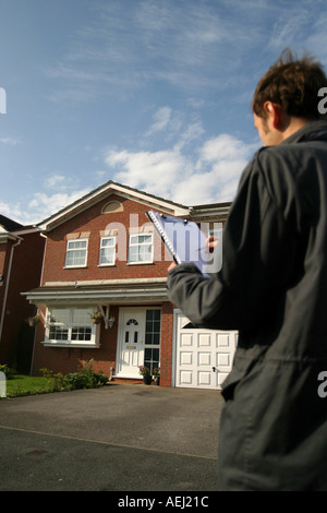 Un jeune homme qui travaille comme arpenteur effectue un sondage auprès d'un logement neuf en amont d'une vente immobilière. Banque D'Images