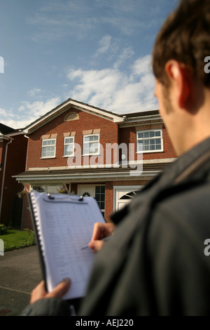 Un jeune homme qui travaille comme arpenteur effectue un sondage auprès d'un logement neuf en amont d'une vente immobilière. Banque D'Images