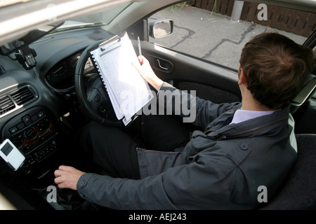 Un jeune homme qui travaille comme arpenteur effectue un sondage auprès d'un logement neuf en amont d'une vente immobilière. Banque D'Images