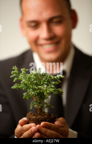 Young Woman holding doucement une petite usine, focus on foreground Banque D'Images