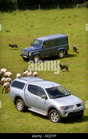 Un Land Rover DEFENDER ET MITSUBISHI L200 PICK UP TRUCK SUR UNE FERME DE MOUTONS GLOUCESTERSHIRE UK Banque D'Images