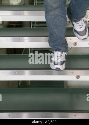 L'homme en jeans walking down steps Banque D'Images