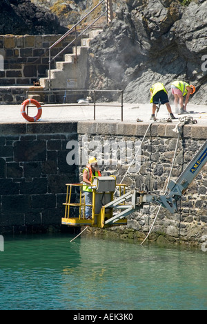 Meneau mur du port à réparer les dégâts causés par des ouvriers spécialisés et l'accès à l'aide de forage équipement Cornwall England UK Banque D'Images