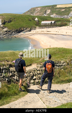 Les marcheurs s'arrêtent sur South West Coast Path. Admirez la plage de bord de mer à Church Cove Gunwalloe Cornwall & Church of Saint Winwaloe, un bâtiment classé au Royaume-Uni de catégorie I. Banque D'Images