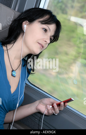 Belle jeune femme rêvant d'un train d'écouter de la musique sur un lecteur mp3 type ipod Banque D'Images