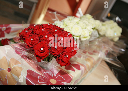 Un bouquet de fleurs roses rouges avec des bijoux en attente à côté de demoiselles bouquets sur un matin de jour de mariage Banque D'Images